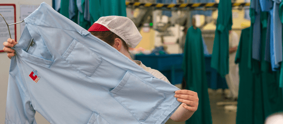 Chica sujetando casaca de SCS en lavandería industrial Amica